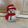 Người tuyết cầm bông tuyết in 3D đội mũ đỏ và quàng khăn đỏ
